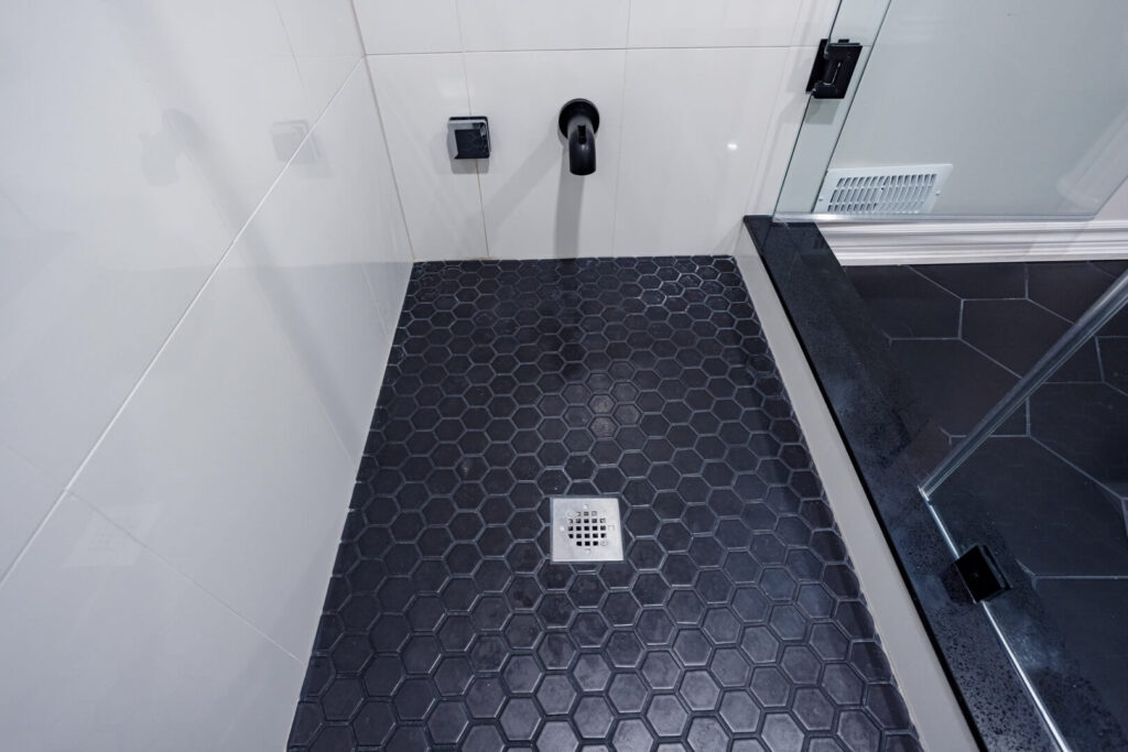 hexagon black tile shower flooring with water tap and drain intsalled