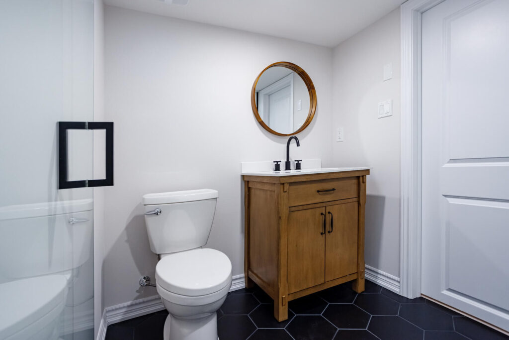 minimalist bathroom renovation with vintage wooden vanity and wooden framed round mirror with white toilet seat