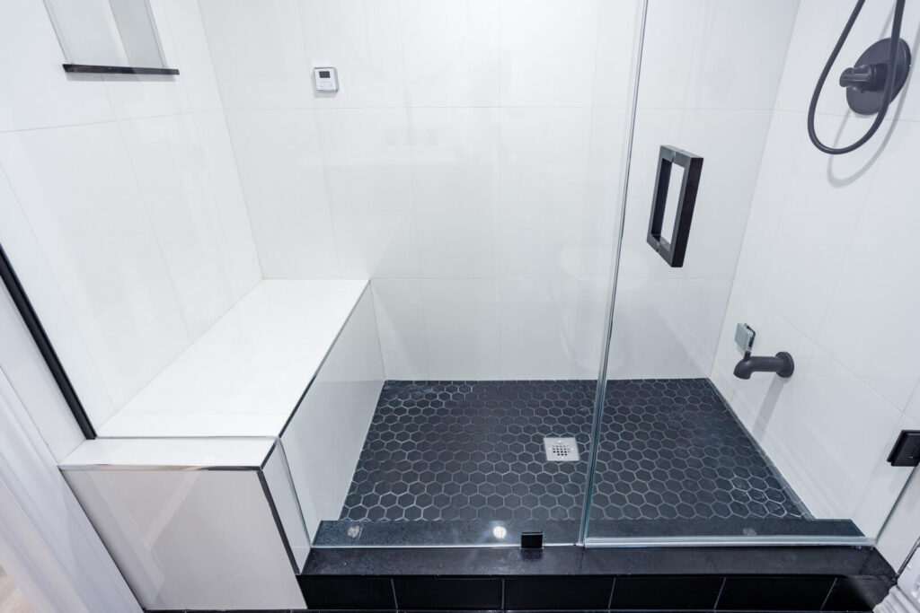 hexagon black tile shower flooring with white tiles shower wall and siting bench