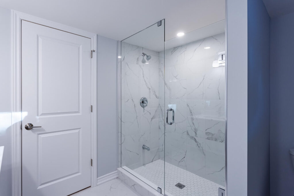 Marble tiles shower wall with two fold glass door and flooring