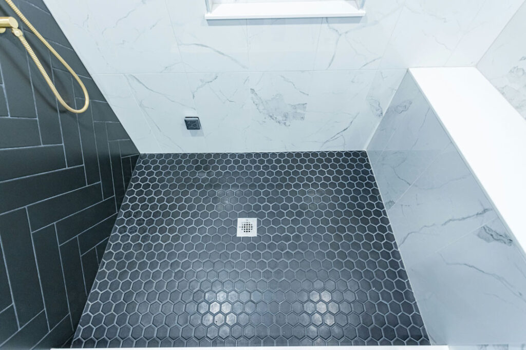 hexagon mosaic tile flooring in shower unit with drain