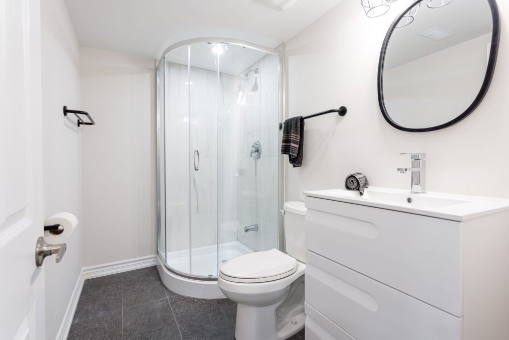 corner shower unit with marble flooring and vanity with toilet seat