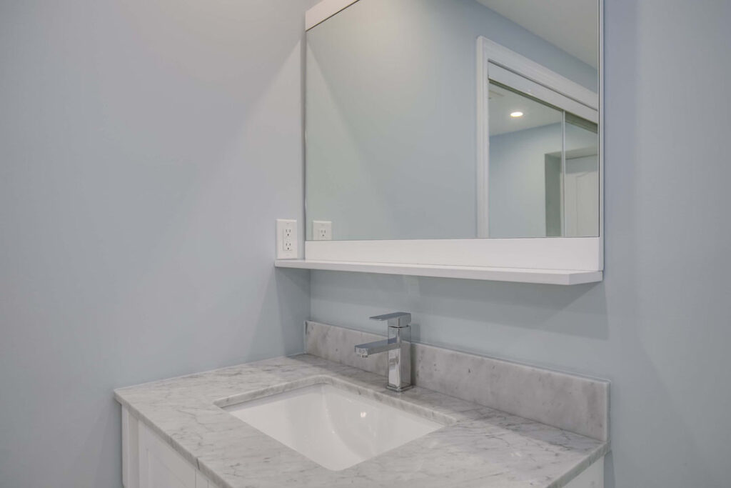marble countertop with tap and mirror with light on top