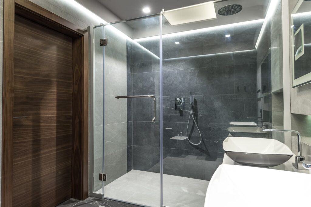 marble tiled bathroom wall with glass two fold door and wall mounted shower heads