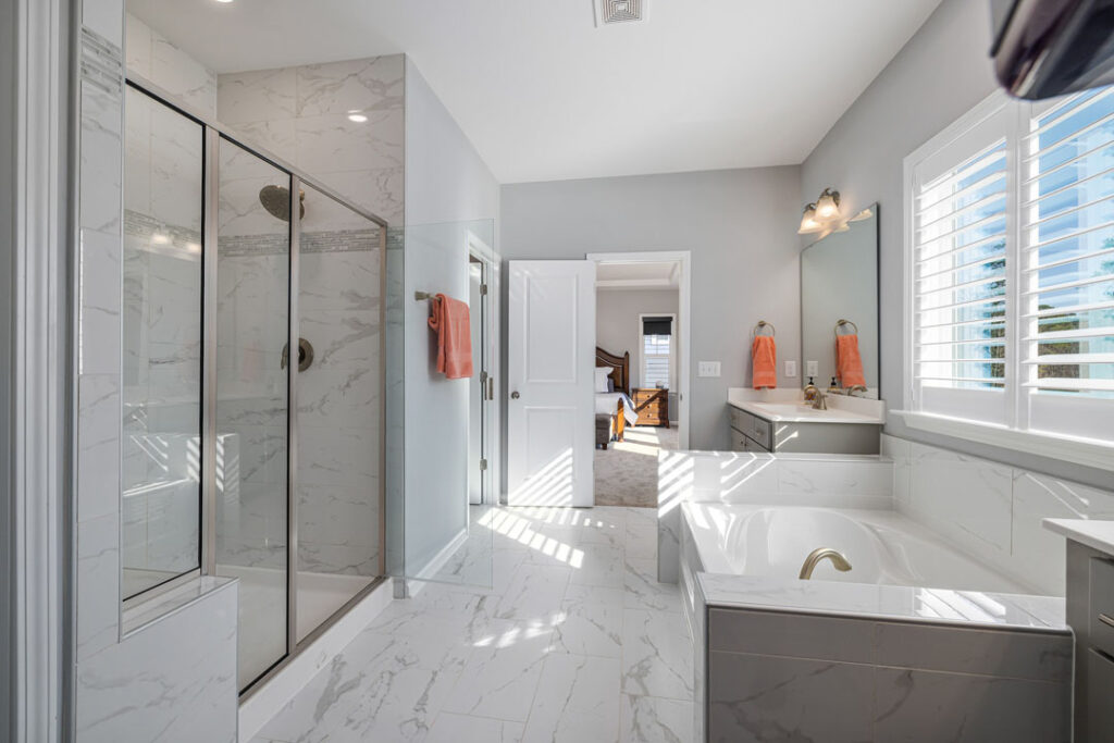 Large bathroom with marble tile flooring and attached bathtub with glass shower door