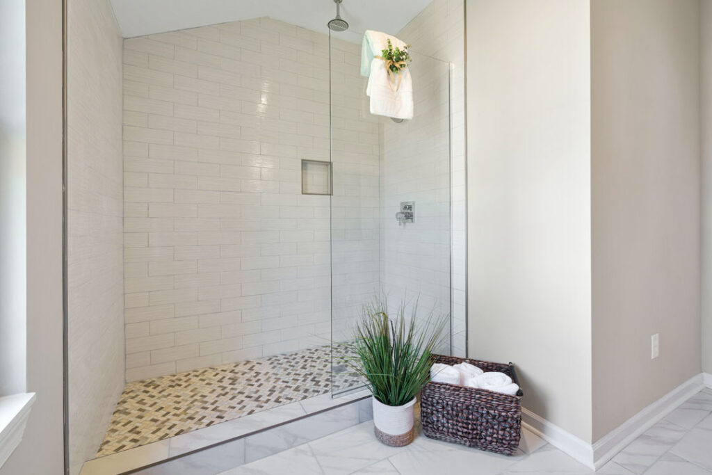 mosaic tile shower unit flooring with subway tiled wall and glass door