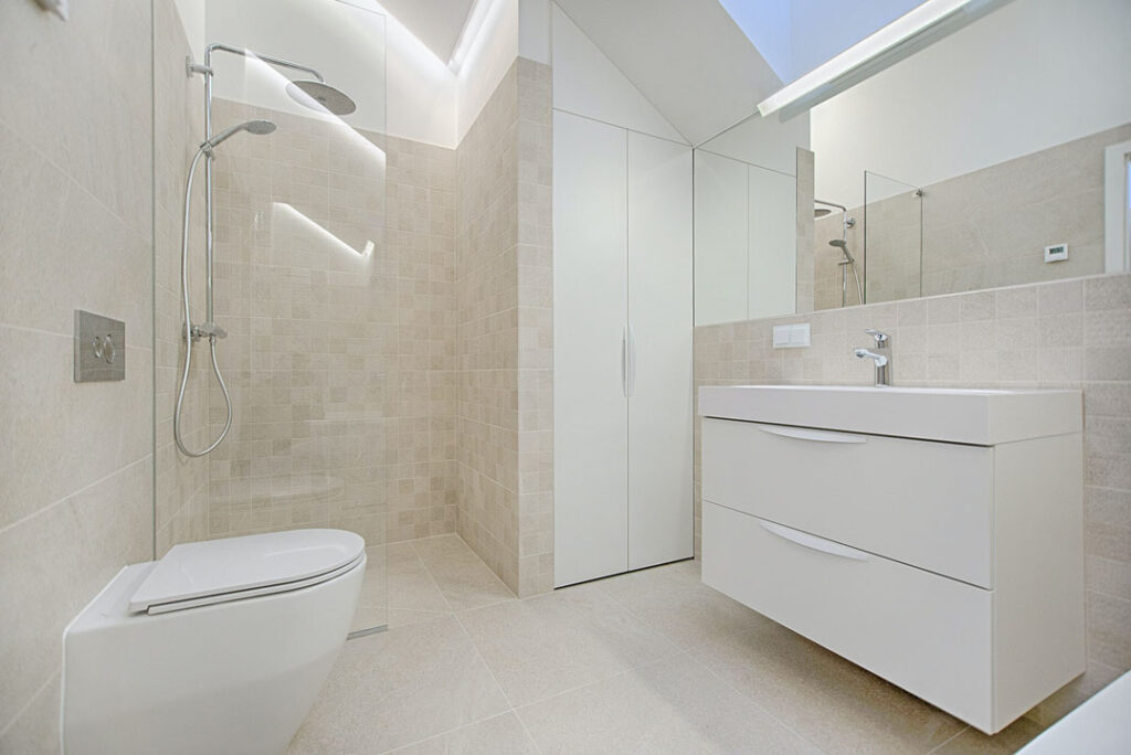 beige bathroom renovation with floating white vanity and beige tiled walls and flooring with toilet seat