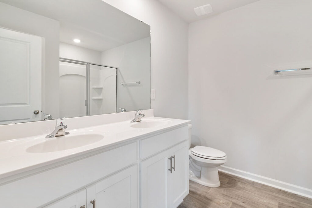 complete white bathroom renovation with vanity and large mirror with toilet seat